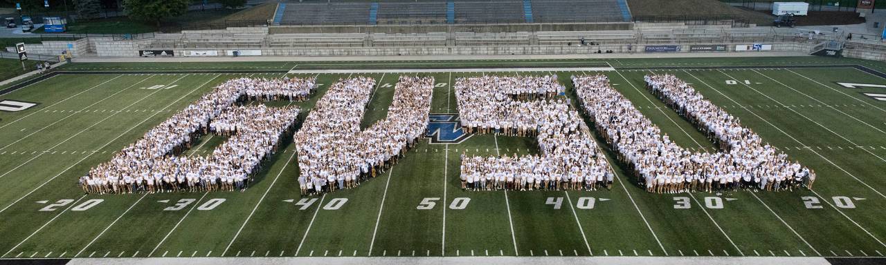GVSU students standing on the football field in the formation of the letters GVSU.
